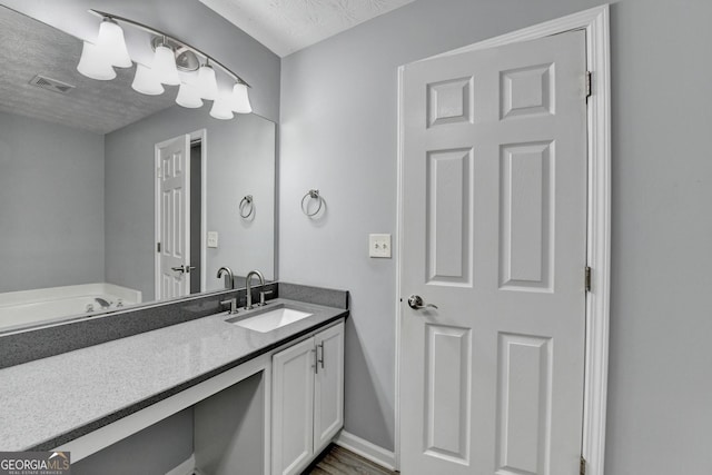 bathroom featuring visible vents, a textured ceiling, vanity, and baseboards