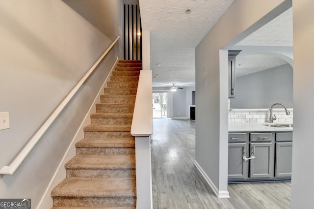 stairway with wood finished floors, baseboards, and a textured ceiling