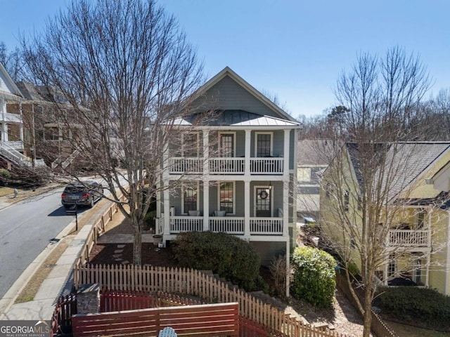 greek revival house featuring covered porch, fence, a standing seam roof, and metal roof