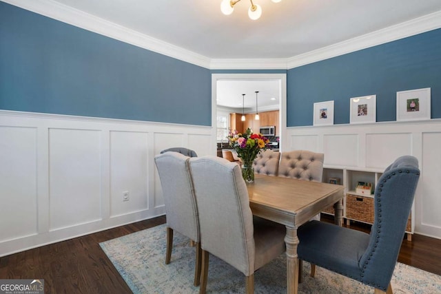 dining space featuring a wainscoted wall, a decorative wall, wood finished floors, and crown molding