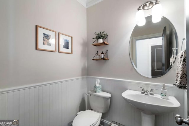 bathroom with a wainscoted wall, a sink, and toilet