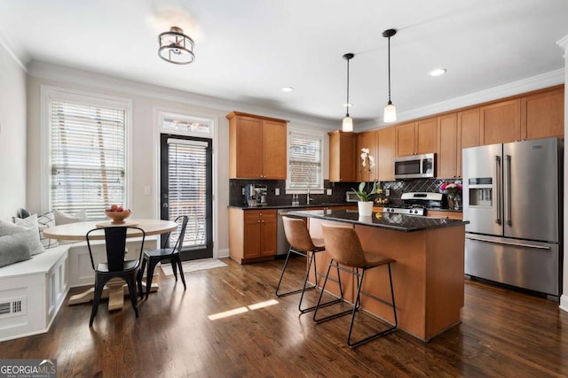 kitchen featuring appliances with stainless steel finishes, dark countertops, dark wood-style flooring, and crown molding