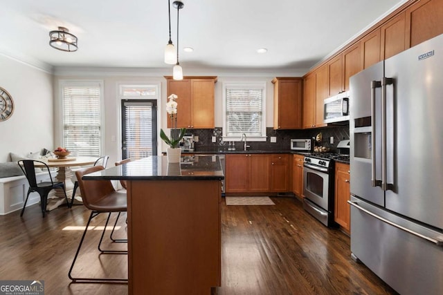 kitchen featuring a breakfast bar area, stainless steel appliances, decorative backsplash, a center island, and dark wood finished floors