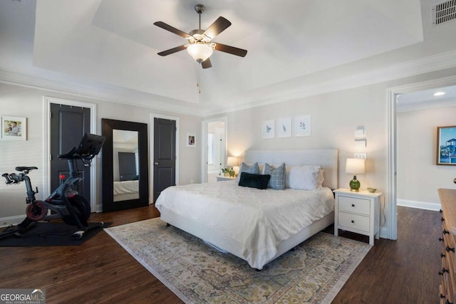 bedroom featuring dark wood-type flooring, a raised ceiling, and visible vents