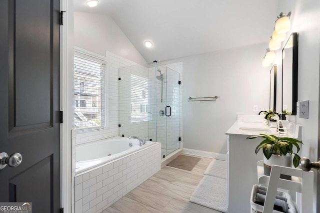 bathroom featuring a garden tub, double vanity, vaulted ceiling, a sink, and a shower stall