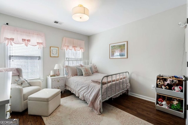 bedroom with visible vents, baseboards, and wood finished floors