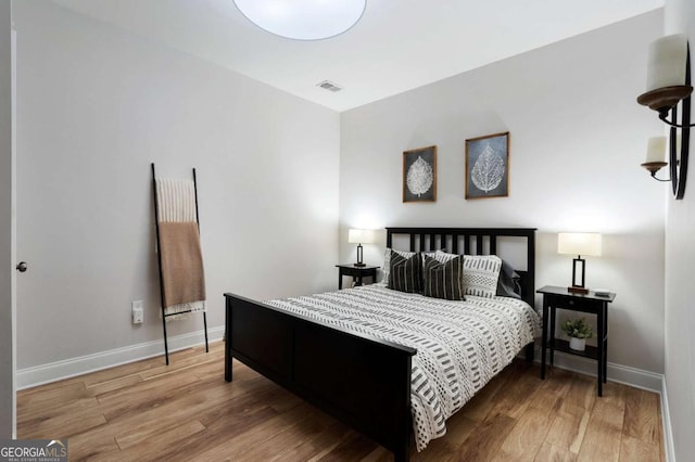 bedroom with wood finished floors, visible vents, and baseboards