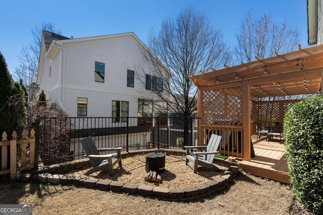 rear view of house featuring fence, a fire pit, a wooden deck, and a pergola