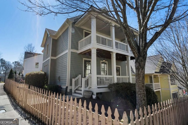 neoclassical / greek revival house with a fenced front yard, covered porch, and a balcony