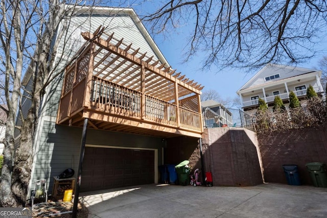 rear view of house featuring driveway, an attached garage, and a pergola