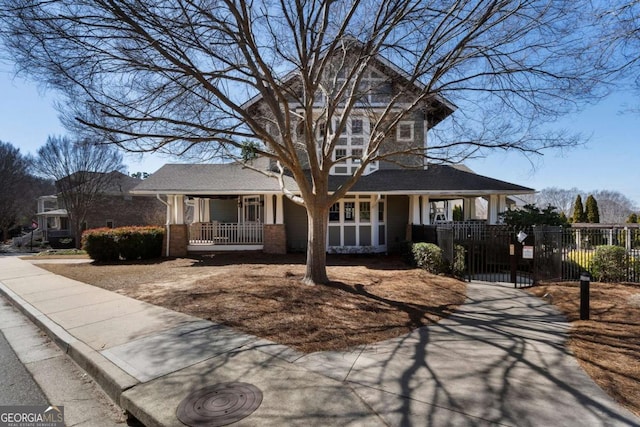 view of front of home featuring a porch, a gate, brick siding, and a fenced front yard