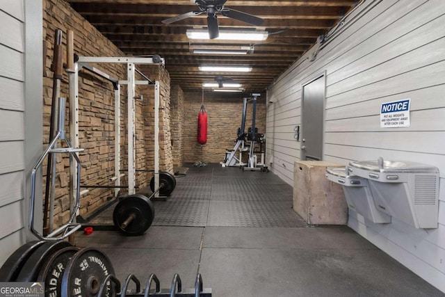 exercise room with brick wall and a ceiling fan