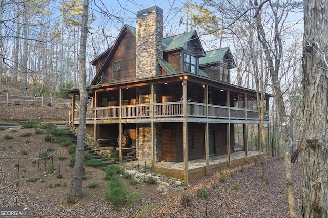 rear view of house featuring a patio area, a chimney, and a wooden deck