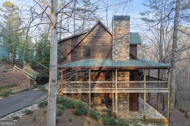 back of property featuring a shingled roof and a chimney