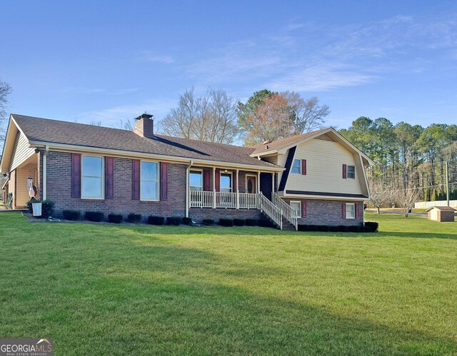 split level home with brick siding, a chimney, a porch, a gambrel roof, and a front yard