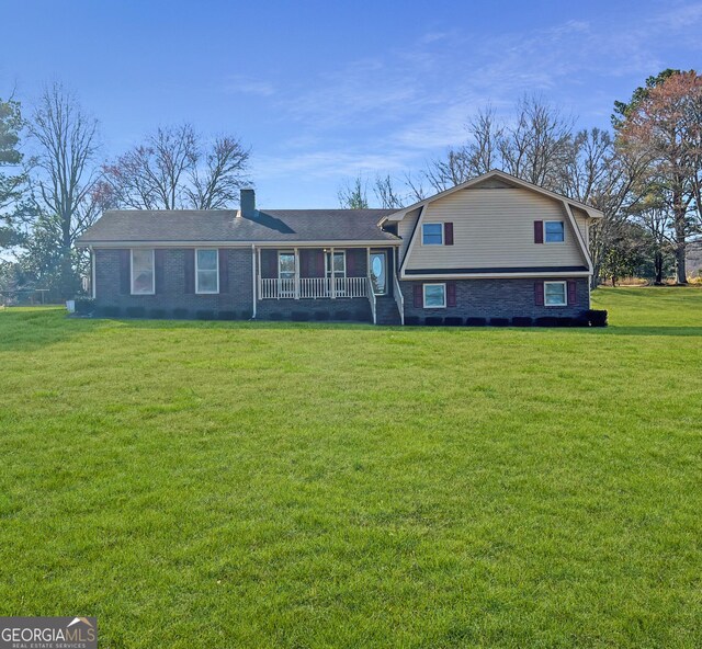 split level home featuring a front lawn, brick siding, a chimney, and a gambrel roof