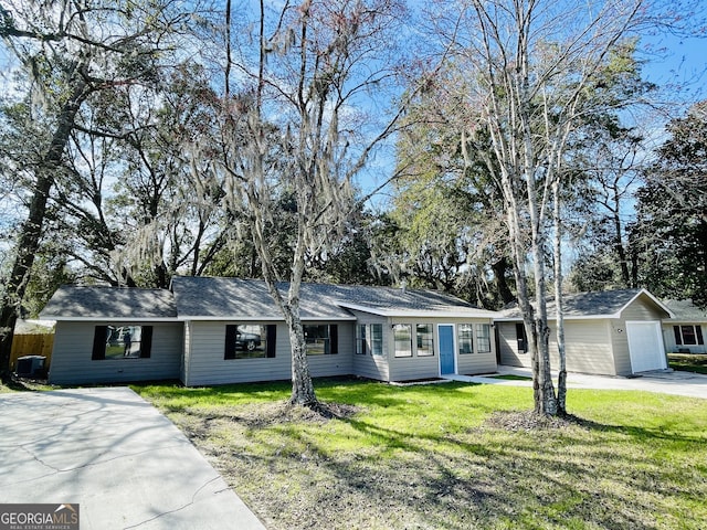 ranch-style house featuring an attached garage, driveway, a front yard, and an outdoor structure