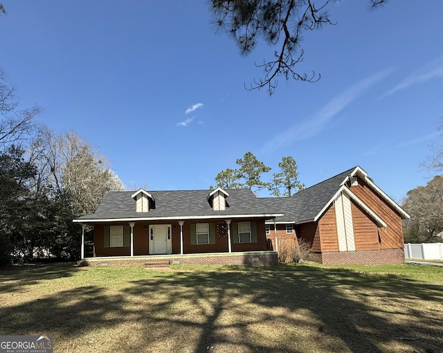 view of front of property with covered porch, fence, brick siding, and a front yard