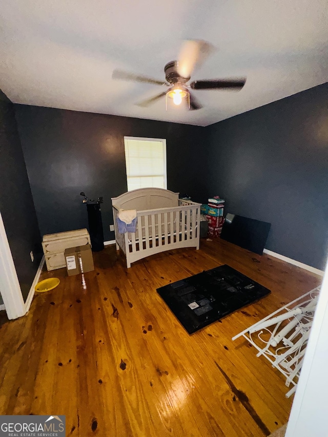 unfurnished bedroom with wood finished floors, a ceiling fan, and baseboards