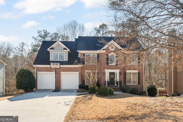 colonial inspired home with concrete driveway, brick siding, and an attached garage