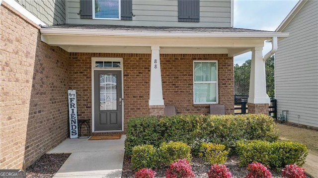 doorway to property featuring covered porch and brick siding