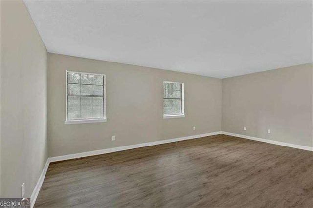 empty room featuring dark wood-style floors and baseboards