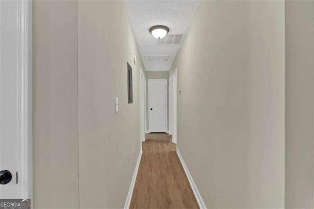 hallway featuring baseboards, visible vents, and light wood finished floors