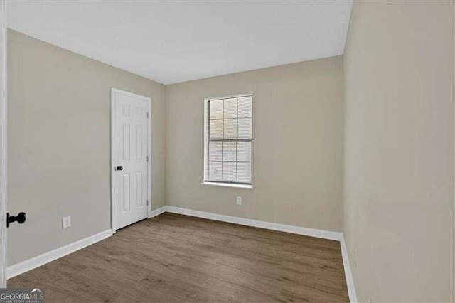 empty room featuring wood finished floors and baseboards