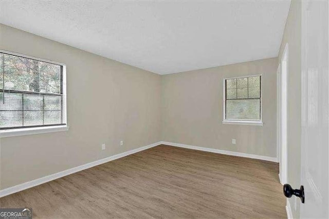 unfurnished room with wood finished floors and baseboards