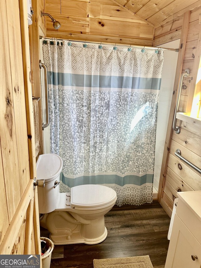 bathroom featuring lofted ceiling, a shower with shower curtain, toilet, wood walls, and wood finished floors