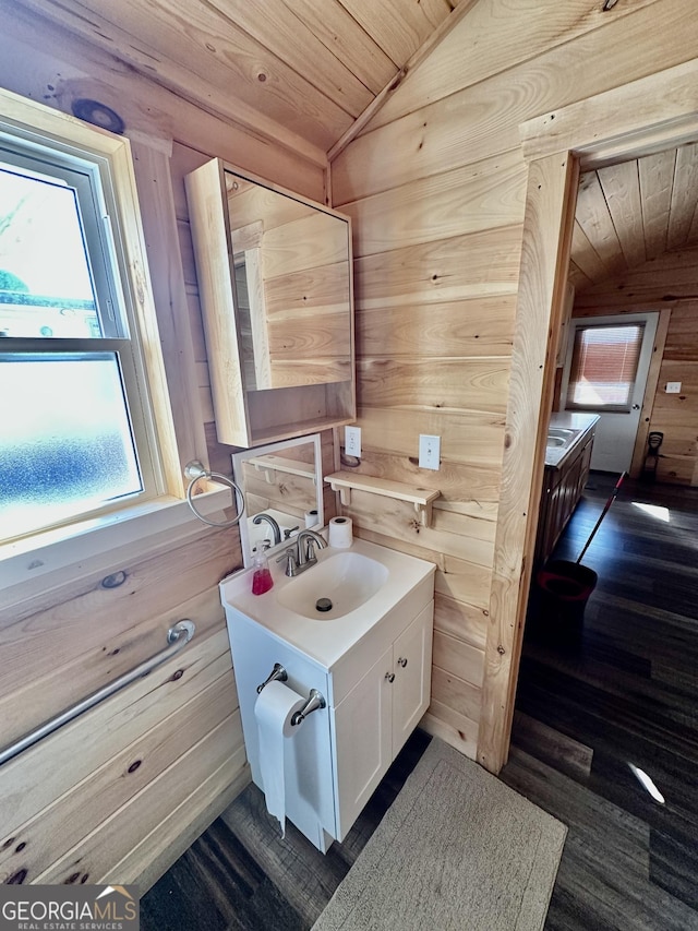 bathroom featuring wood ceiling, vaulted ceiling, wooden walls, and vanity