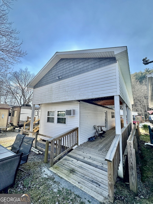 rear view of house featuring an AC wall unit and a wooden deck