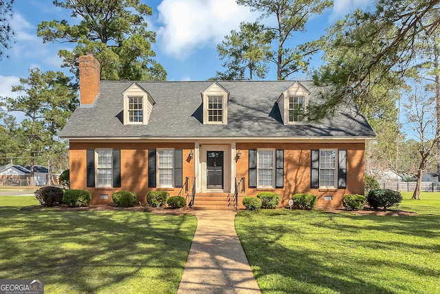 new england style home with brick siding, roof with shingles, a chimney, a front yard, and crawl space