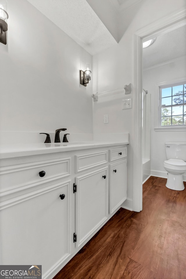 bathroom featuring toilet, shower / bath combination, wood finished floors, vanity, and baseboards