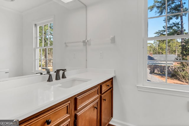 bathroom featuring baseboards, crown molding, vanity, and toilet