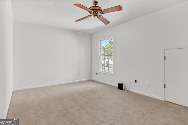 spare room with a textured ceiling, carpet floors, ornamental molding, and ceiling fan