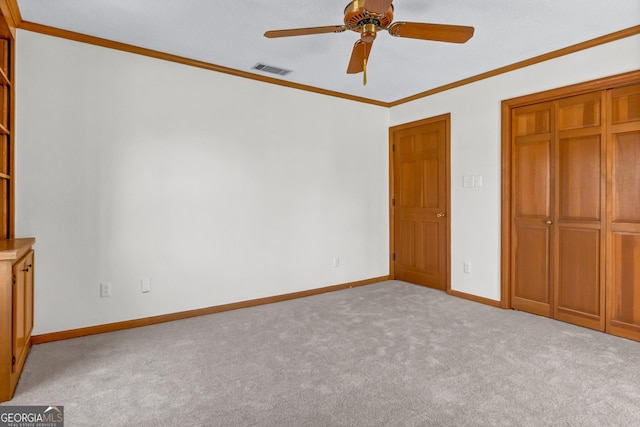 unfurnished bedroom with carpet, a closet, visible vents, ornamental molding, and baseboards