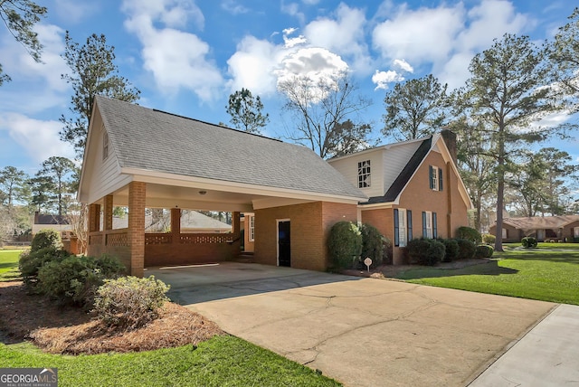 view of front of property featuring driveway, roof with shingles, a front lawn, a carport, and brick siding