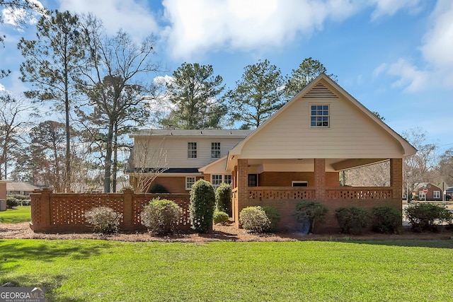 view of front of home with a porch, fence, a front lawn, and brick siding