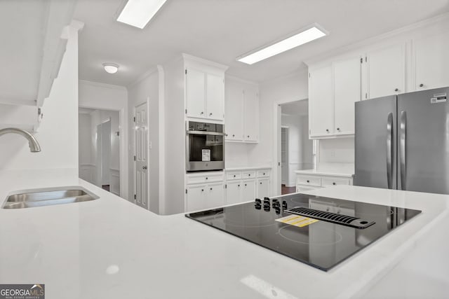 kitchen featuring stainless steel appliances, light countertops, ornamental molding, white cabinets, and a sink