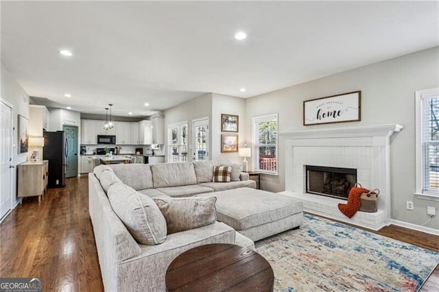 living area featuring recessed lighting, dark wood-style flooring, a fireplace, and baseboards