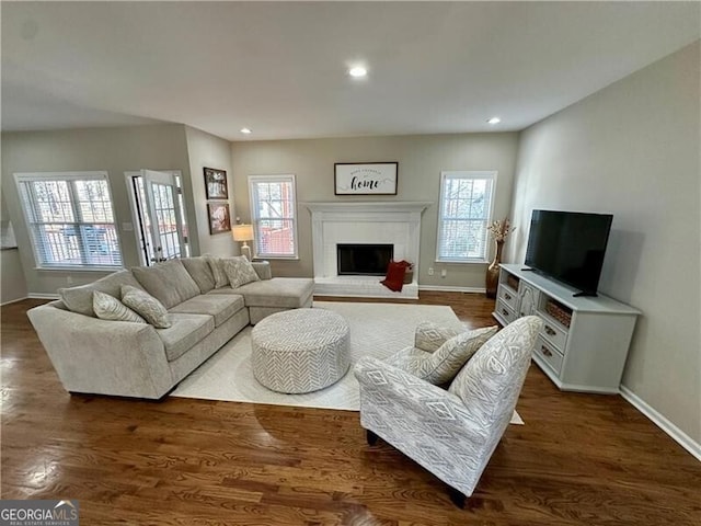 living room featuring dark wood-style floors, a wealth of natural light, a brick fireplace, and recessed lighting