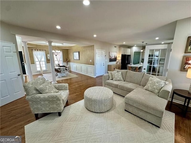 living room with decorative columns, a wainscoted wall, wood finished floors, a notable chandelier, and recessed lighting