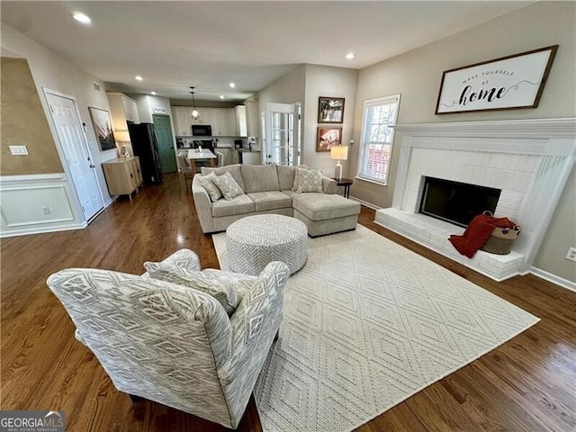 living room featuring dark wood-style floors, a brick fireplace, and recessed lighting