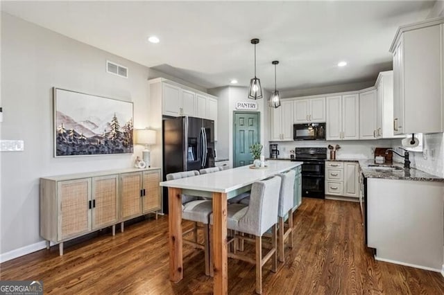 kitchen featuring black microwave, range, a kitchen island, refrigerator with ice dispenser, and a sink