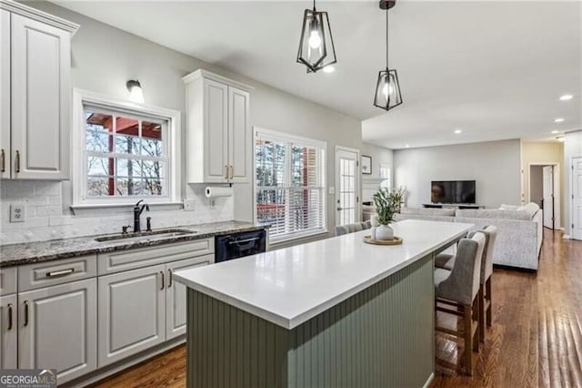 kitchen featuring backsplash, a sink, dark wood finished floors, and a center island