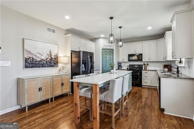 kitchen featuring fridge with ice dispenser, range, black microwave, a center island, and a sink