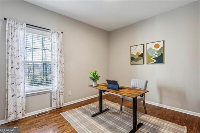 office area featuring a wealth of natural light, wood finished floors, visible vents, and baseboards