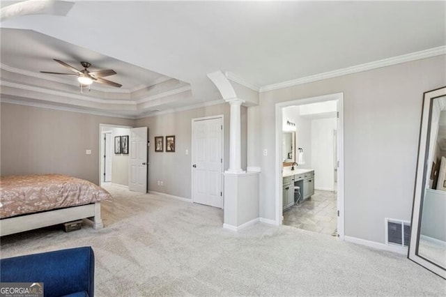 unfurnished bedroom with a tray ceiling, decorative columns, light colored carpet, visible vents, and baseboards