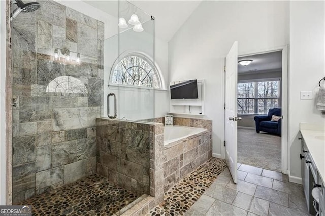 bathroom with a tile shower, a garden tub, vanity, and vaulted ceiling